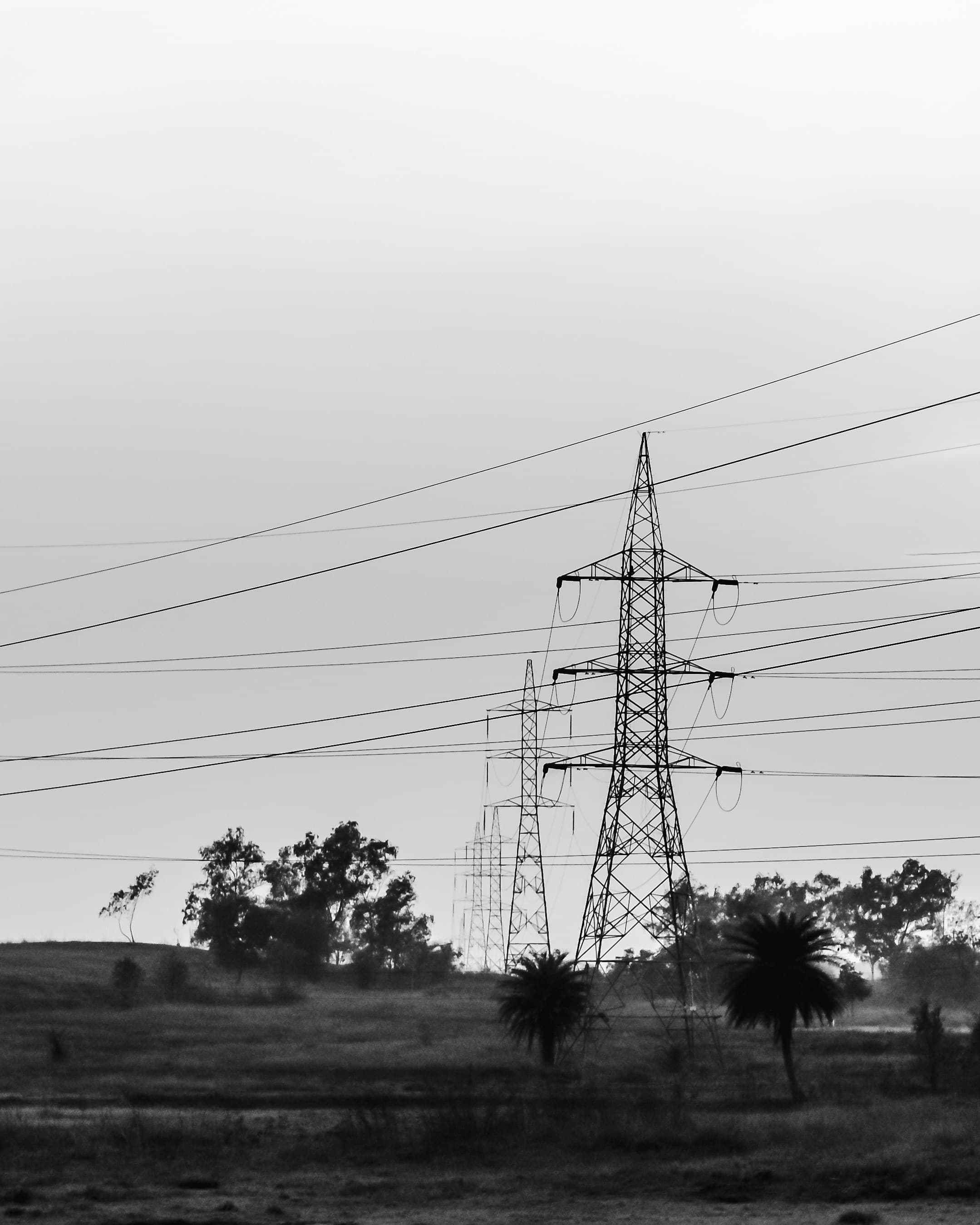 High voltage power transmission lines and towers in open landscape aerial view